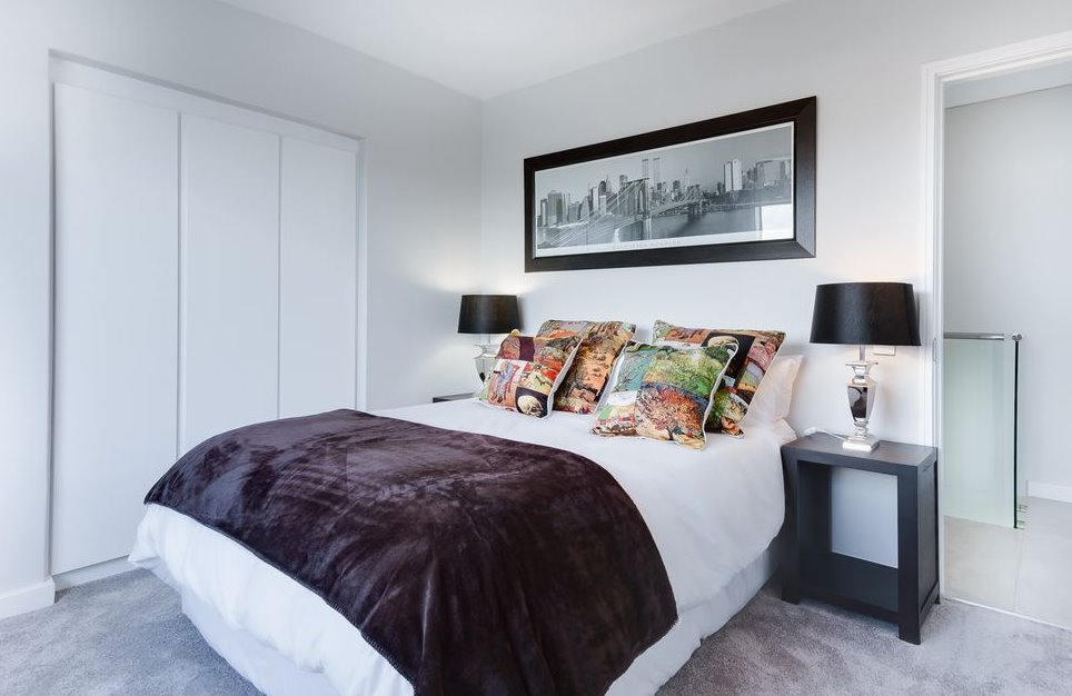 A bright bedroom with a window shade filtering morning light