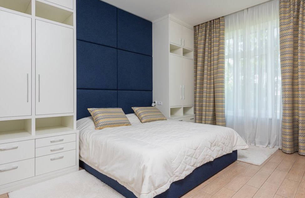A bedroom with layered sheer and patterned curtains at a large window
